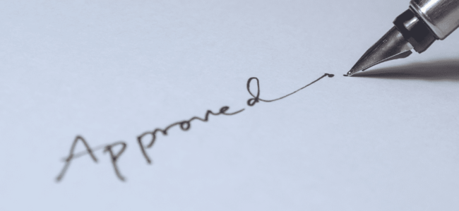 caneta escrevendo a palavra aproved em um papel em branco