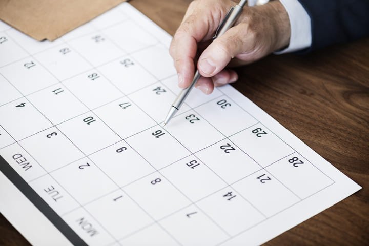 mão masculina escrevendo em um calendário simulando prazos do registro de marcas