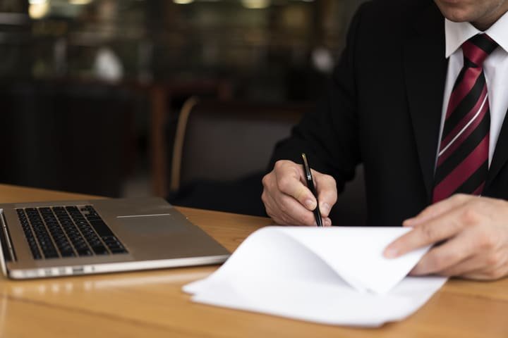 Homem escrevendo em papel representando a criação do direito autoral
