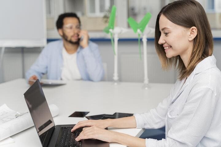 Mulher digitando e sorrindo em frente a um notbook simulando pesquisa de marcas registradas