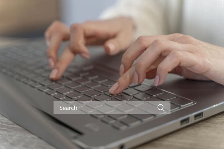 Mãos de mulher digitando fazendo uma pesquisa de registro de marcas em um computador