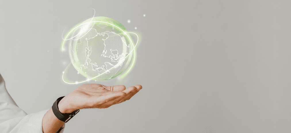 Mão esticada direcionando a um holograma do mundo com luzes verdes em volta representando a propriedade intelectual no desenvolvimento sustentável