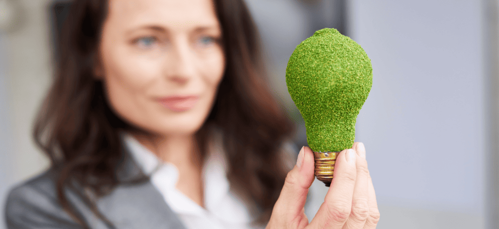 Mulher segura lâmpada com grama ao redor representando propriedade intelectual e patentes verdes