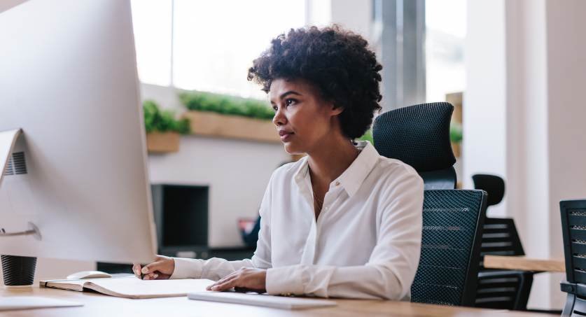 Mulher em escritório frente a um computador fazendo monitoramento de marca registrada