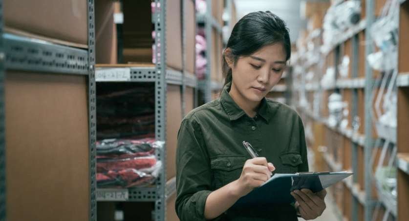 Empreendedora em estoque de roupas mexendo em Ipad pesquisando sobre registro marca de roupa